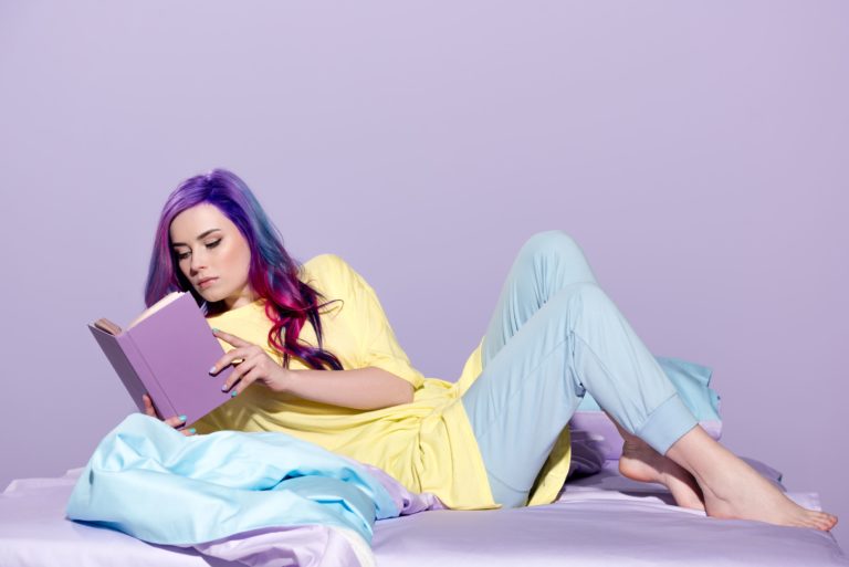 concentrated-young-woman-with-colorful-hair-readin-DN34GGU